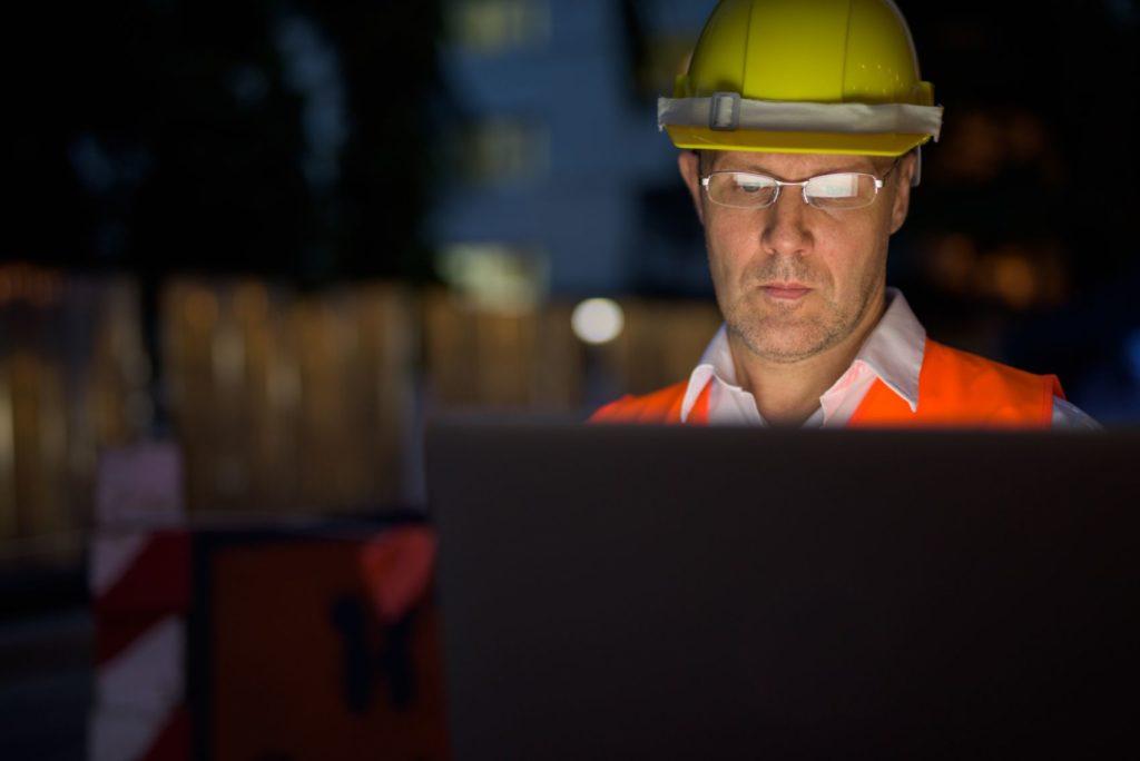 Construction worker looking at a laptop with 6D Road Scanning data.