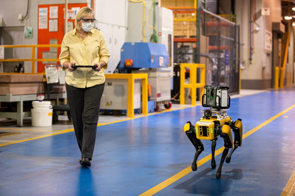 Ford Digital Manufacturing Engineer Paula Wiebelhaus walks with Fluffy. Wiebelhaus controls the robotic pup with the video-game-style tablet in her hands.