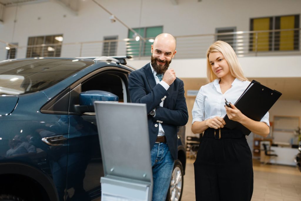 Car dealership sales consultant with a customer.